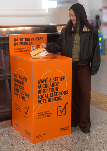 Rectangular vote box, featuring orange colouring, the Auckland Council logo, a tick icon and the text "Want a better Auckland? Drop your local elections vote in here."