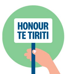 A brown hand holds a sign with text that says "Honour Te Tititi" against a green circular background.
