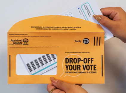 Hand placing a voting paper into an official orange envelope.
