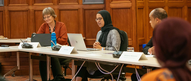 Three people sitting at a desk attending a meeting. 